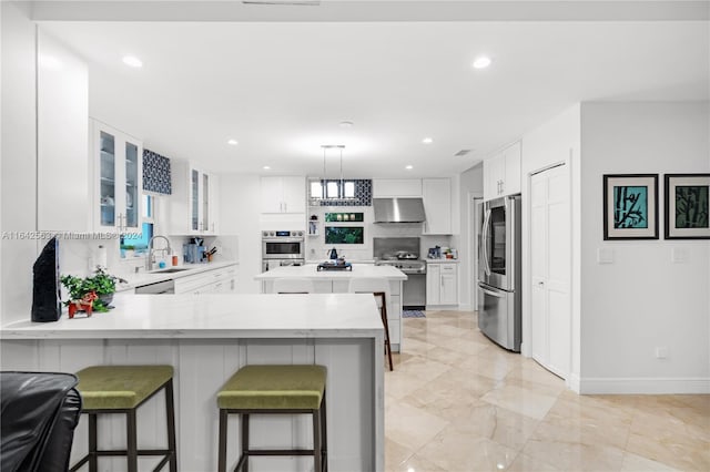 kitchen with appliances with stainless steel finishes, glass insert cabinets, range hood, light countertops, and white cabinetry