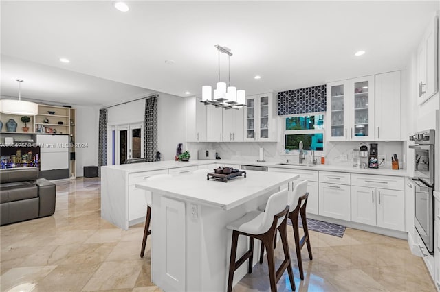 kitchen with a center island, a breakfast bar area, light countertops, hanging light fixtures, and glass insert cabinets