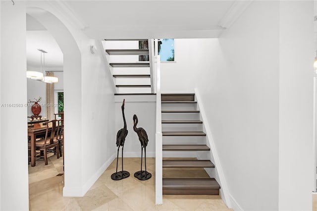 stairway featuring baseboards, arched walkways, and ornamental molding