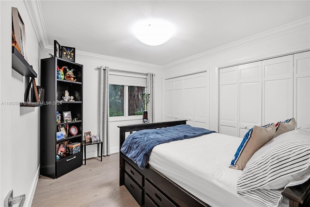 bedroom featuring light wood-style flooring, ornamental molding, and two closets