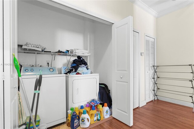 washroom with wood-type flooring, washer and clothes dryer, and ornamental molding