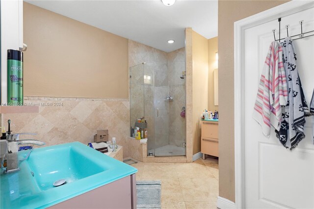 bathroom with tile patterned flooring, walk in shower, vanity, and tile walls