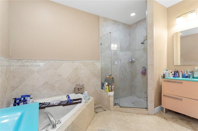 bathroom with tile walls, tile patterned flooring, shower with separate bathtub, and vanity