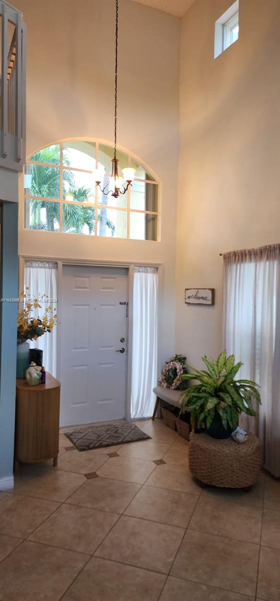 tiled foyer entrance with a high ceiling and a notable chandelier