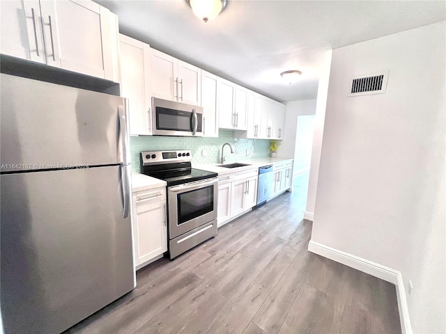 kitchen with sink, stainless steel appliances, decorative backsplash, and light wood-type flooring