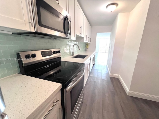 kitchen featuring backsplash, dark hardwood / wood-style floors, white cabinets, sink, and stainless steel appliances