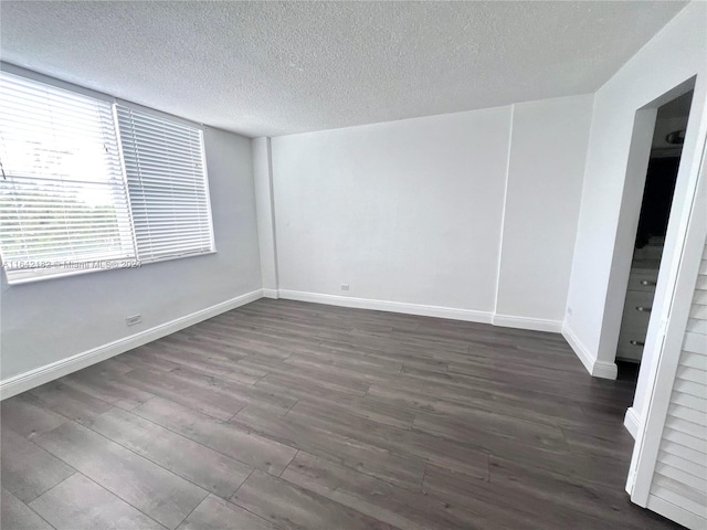 empty room with wood-type flooring and a textured ceiling