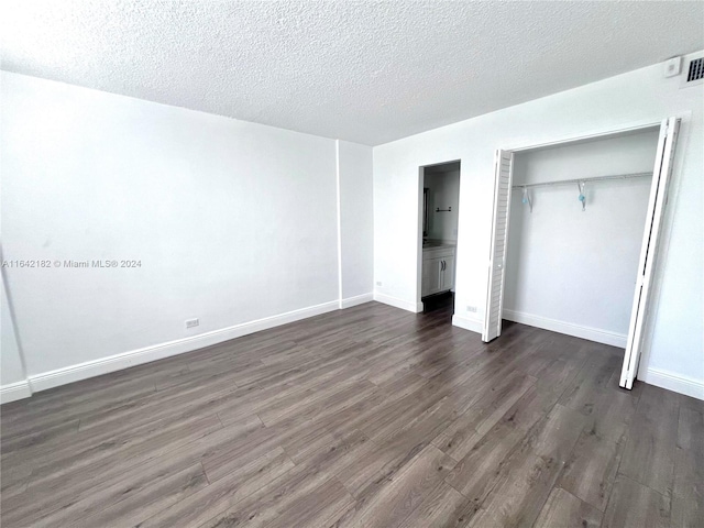 unfurnished bedroom featuring a closet, wood-type flooring, and a textured ceiling