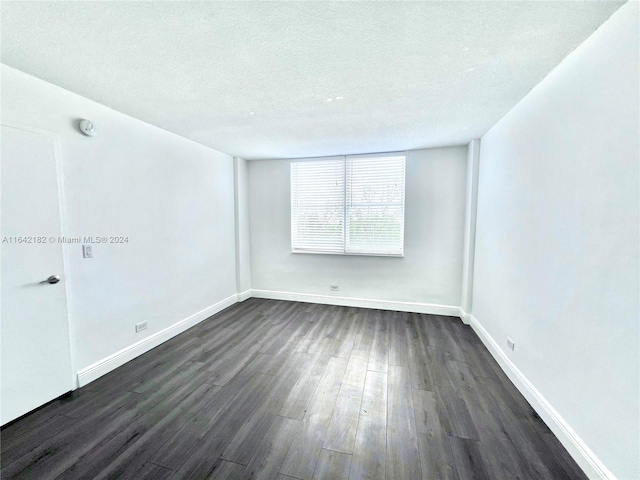 unfurnished room featuring dark hardwood / wood-style floors and a textured ceiling