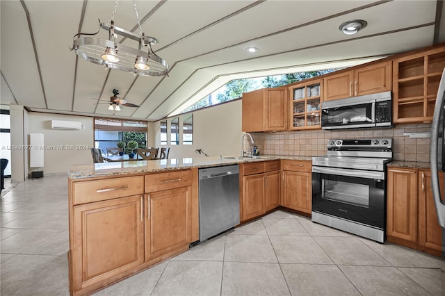 kitchen featuring ceiling fan, appliances with stainless steel finishes, light stone counters, sink, and kitchen peninsula