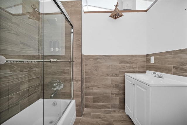 bathroom featuring tile walls, vanity, and shower / bath combination with glass door