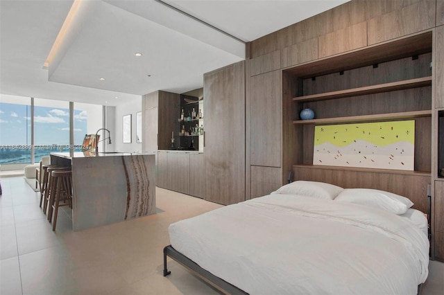 bedroom with sink, floor to ceiling windows, a water view, access to outside, and light tile patterned floors