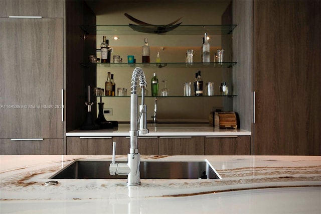 bar featuring sink and light stone countertops