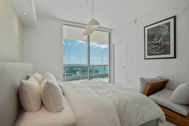 bedroom featuring access to outside, a wall of windows, and a water view