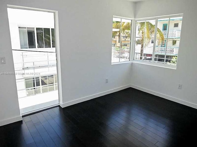 spare room with dark hardwood / wood-style floors and plenty of natural light