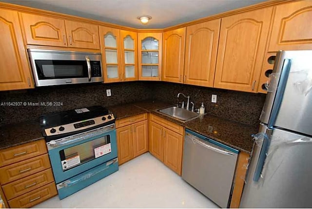 kitchen featuring sink, decorative backsplash, dark stone countertops, and stainless steel appliances