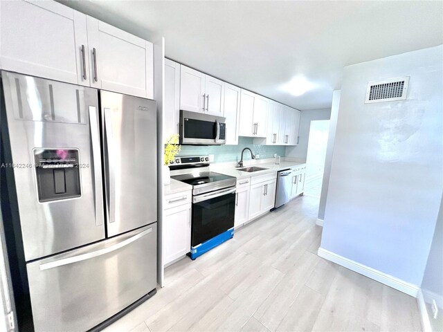 kitchen featuring stainless steel appliances, a sink, visible vents, white cabinetry, and light countertops