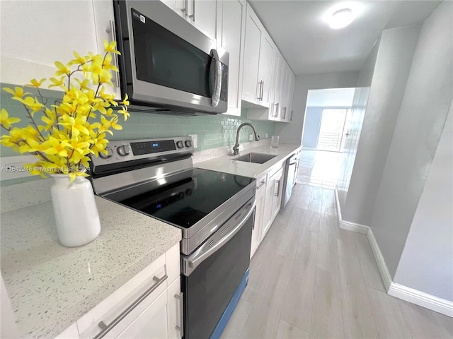 kitchen with backsplash, white cabinetry, light stone countertops, sink, and stainless steel appliances