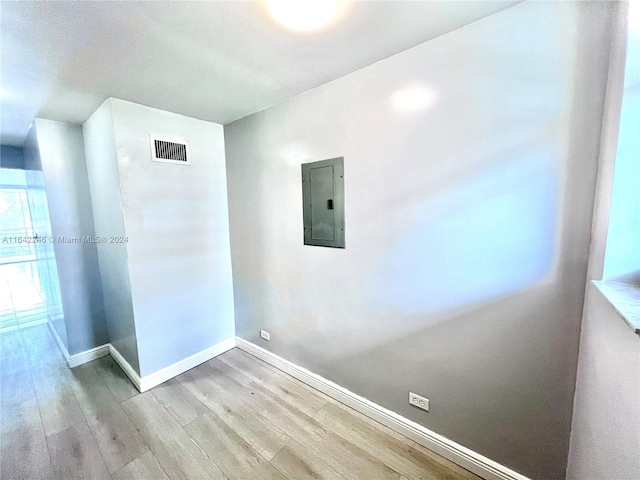 unfurnished room featuring visible vents, wood finished floors, electric panel, and baseboards