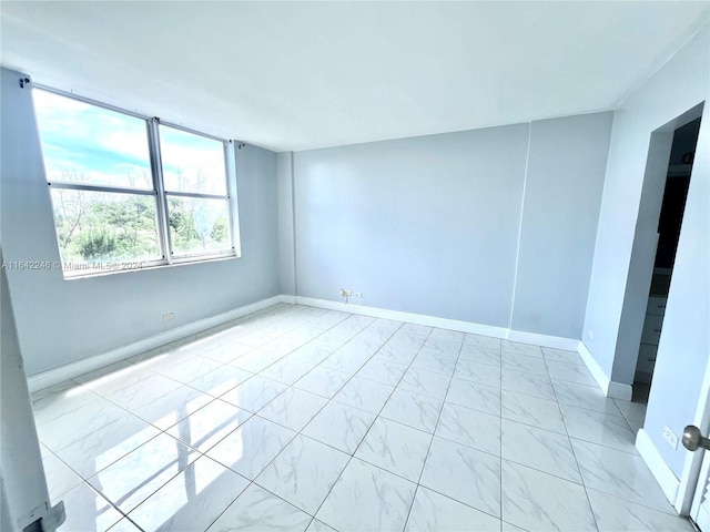 empty room featuring marble finish floor and baseboards