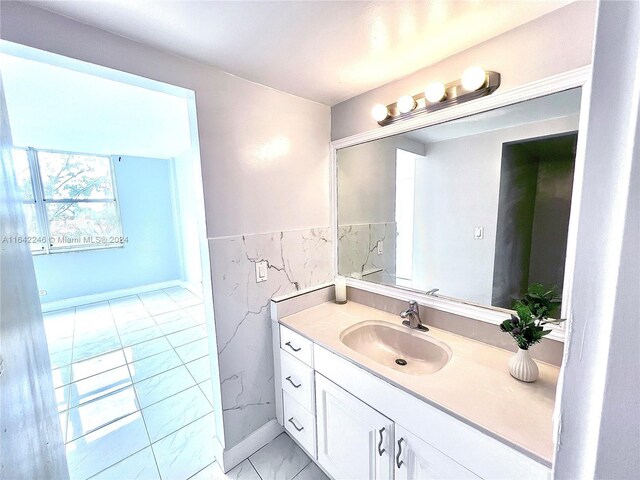 bathroom with marble finish floor, a wainscoted wall, tile walls, and vanity