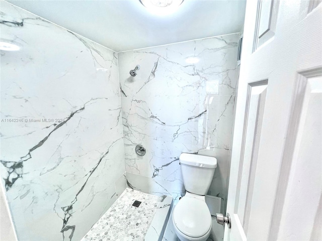 bathroom with toilet and a marble finish shower