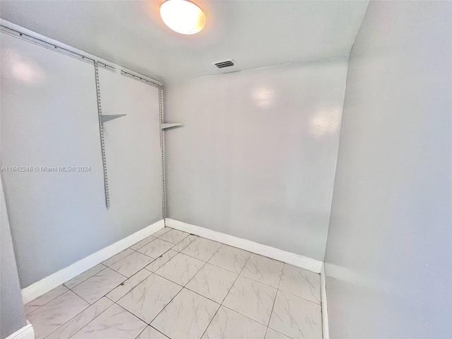 unfurnished room with marble finish floor, baseboards, and visible vents