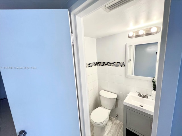 bathroom with toilet, tile walls, and vanity