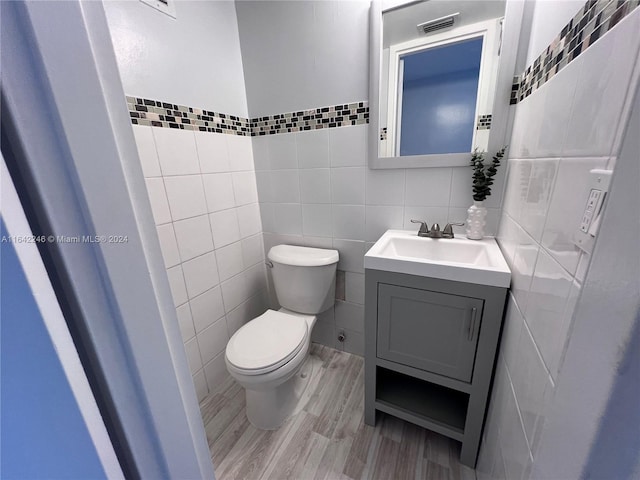 bathroom featuring tile walls, backsplash, vanity, and toilet