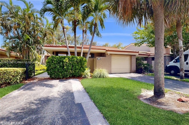 view of front of property featuring a garage, stucco siding, aphalt driveway, a tiled roof, and a front yard