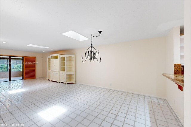 tiled empty room with a notable chandelier and a skylight