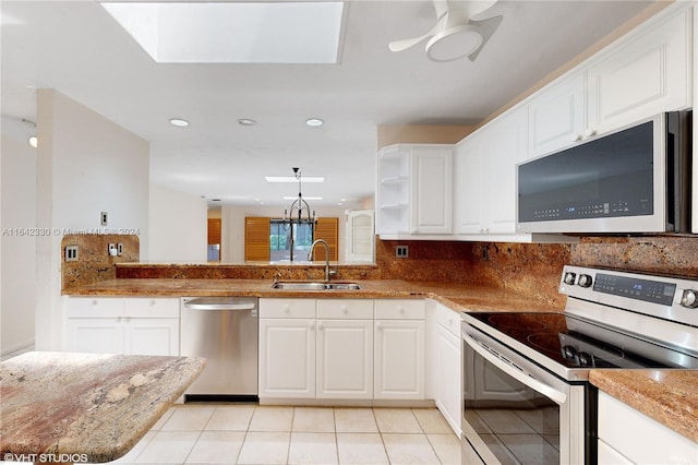 kitchen with light tile patterned floors, stainless steel appliances, a sink, white cabinets, and backsplash