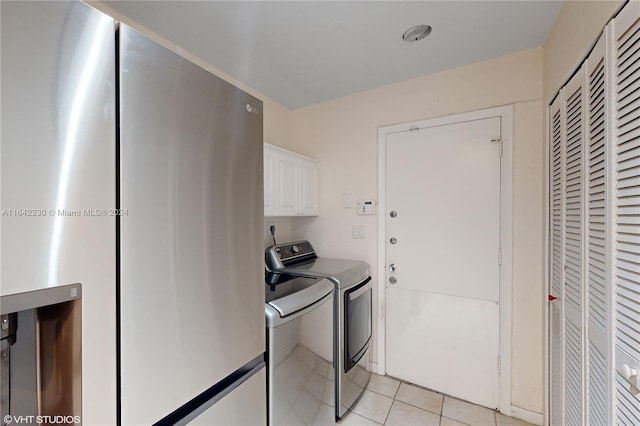 clothes washing area featuring cabinet space, light tile patterned floors, and washer and dryer