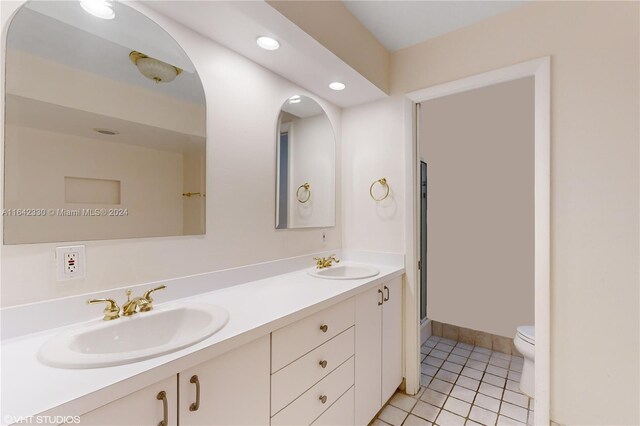 bathroom featuring tile patterned flooring, toilet, and dual bowl vanity