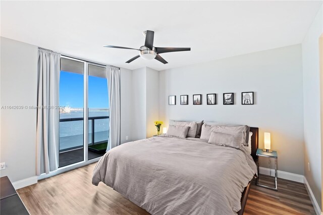 bedroom with hardwood / wood-style flooring, access to exterior, ceiling fan, and a water view