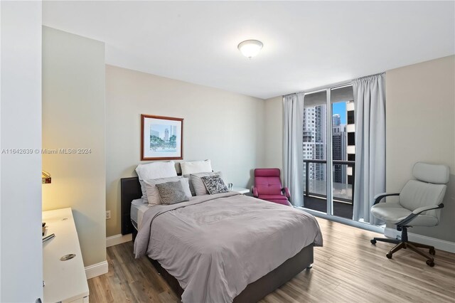 bedroom featuring access to exterior, expansive windows, and hardwood / wood-style flooring