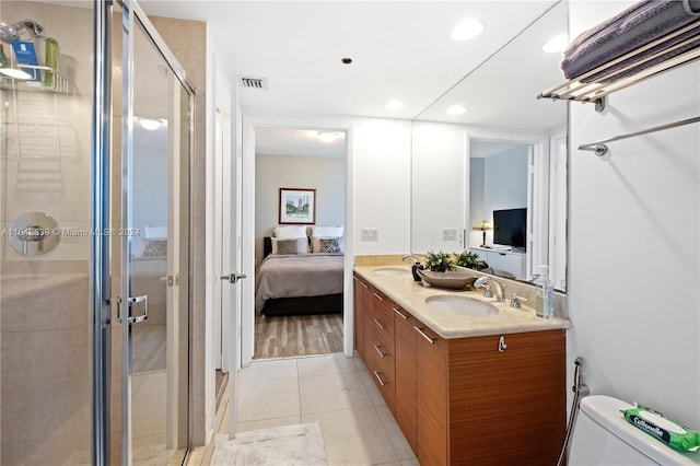 bathroom featuring tile patterned flooring, toilet, a shower with door, and vanity