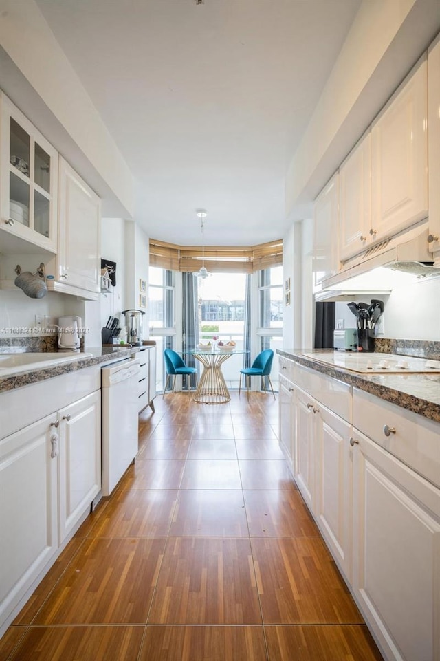 kitchen featuring pendant lighting, dishwasher, hardwood / wood-style flooring, white cabinets, and stone counters