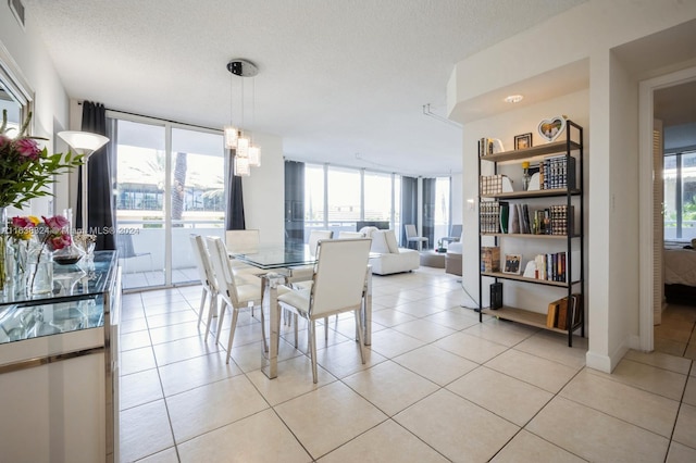 tiled dining space with a textured ceiling and a wall of windows