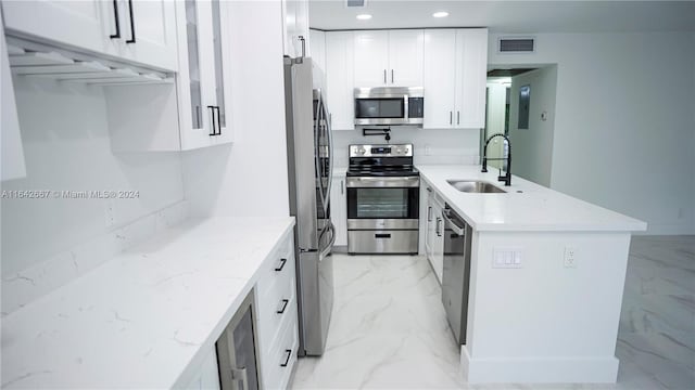 kitchen featuring stainless steel appliances, sink, light stone countertops, white cabinets, and light tile patterned floors