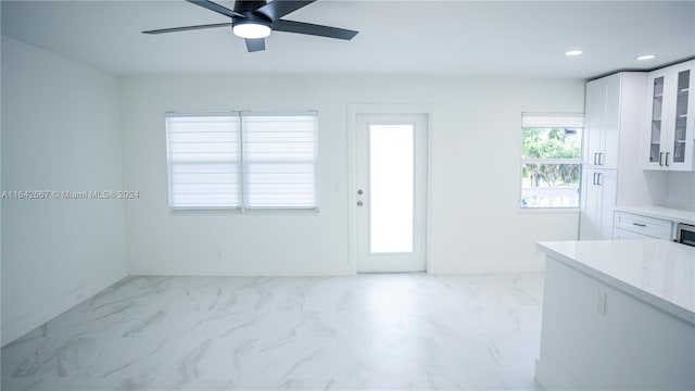 kitchen with white cabinets, ceiling fan, light stone counters, and light tile patterned floors