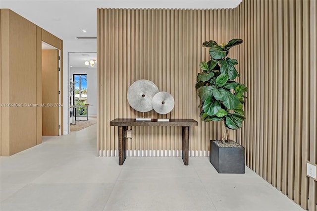 hallway featuring concrete flooring and wooden walls