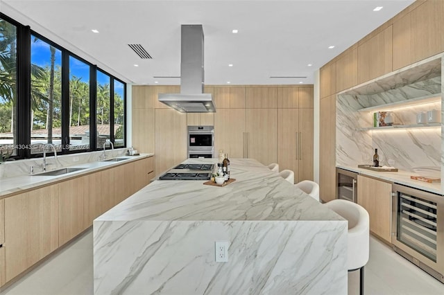 kitchen with light brown cabinets, beverage cooler, sink, and light stone counters