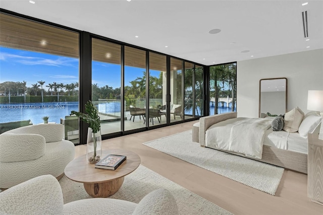 bedroom with expansive windows, access to outside, a water view, and light hardwood / wood-style floors