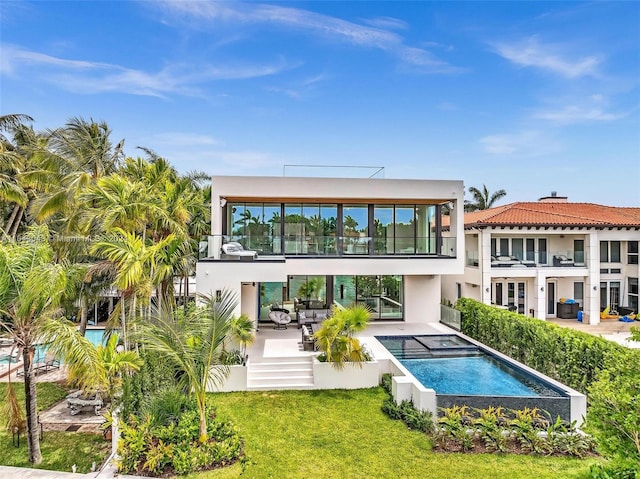 back of house with a patio, a swimming pool with hot tub, an outdoor living space, a lawn, and a balcony