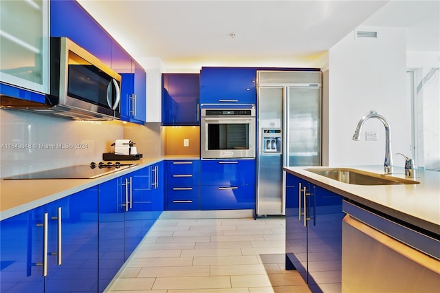 kitchen featuring sink, blue cabinets, light tile patterned flooring, and stainless steel appliances