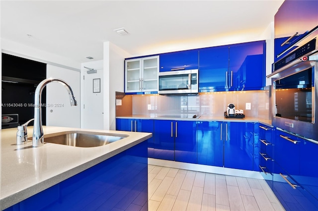 kitchen featuring sink, backsplash, blue cabinetry, and stainless steel appliances