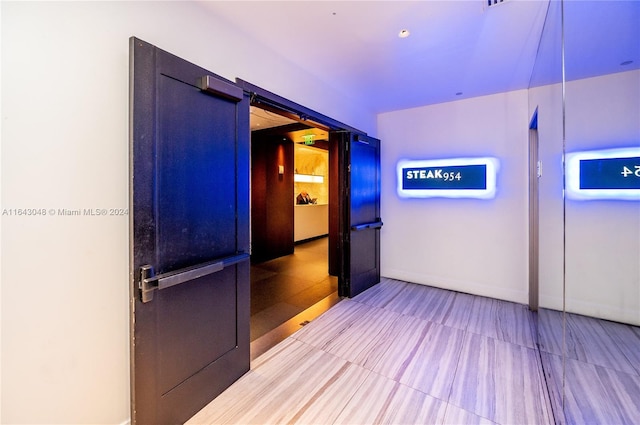 hallway with light tile patterned floors and a barn door