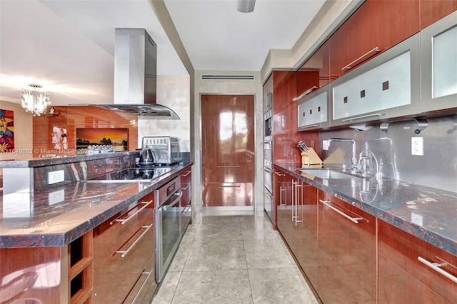 kitchen with dark stone counters, island exhaust hood, oven, black electric stovetop, and a chandelier