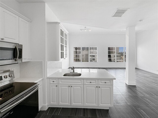 kitchen with backsplash, sink, appliances with stainless steel finishes, dark tile patterned flooring, and white cabinets